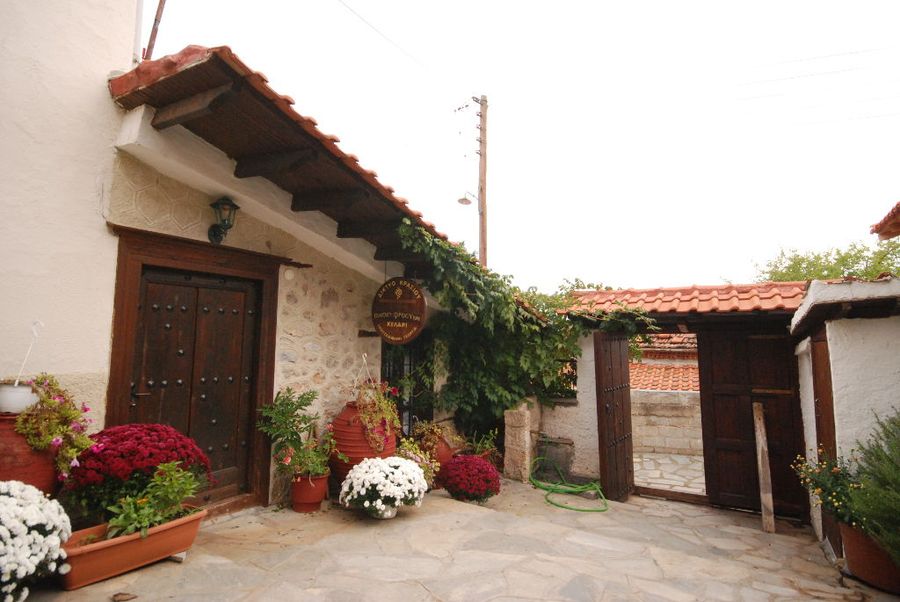 'Dio Fili' winery entrance with wood doors and ceramic pots with flowers on the both sides