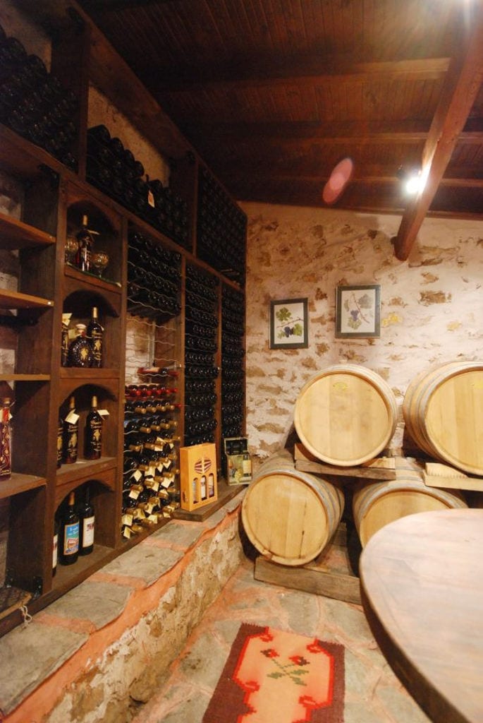 wine bottles in the storage locker and barrels at 'Dio Fili' stone cellar with wood ceiling