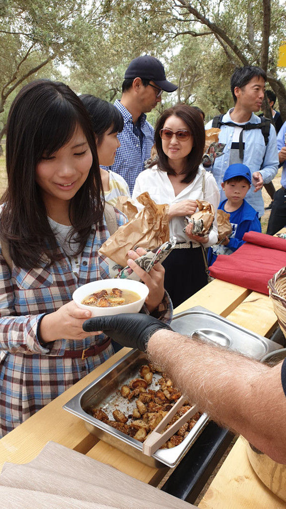 group of Japanese tourists eating soup of mushrooms outside of 'Dirfis' crops