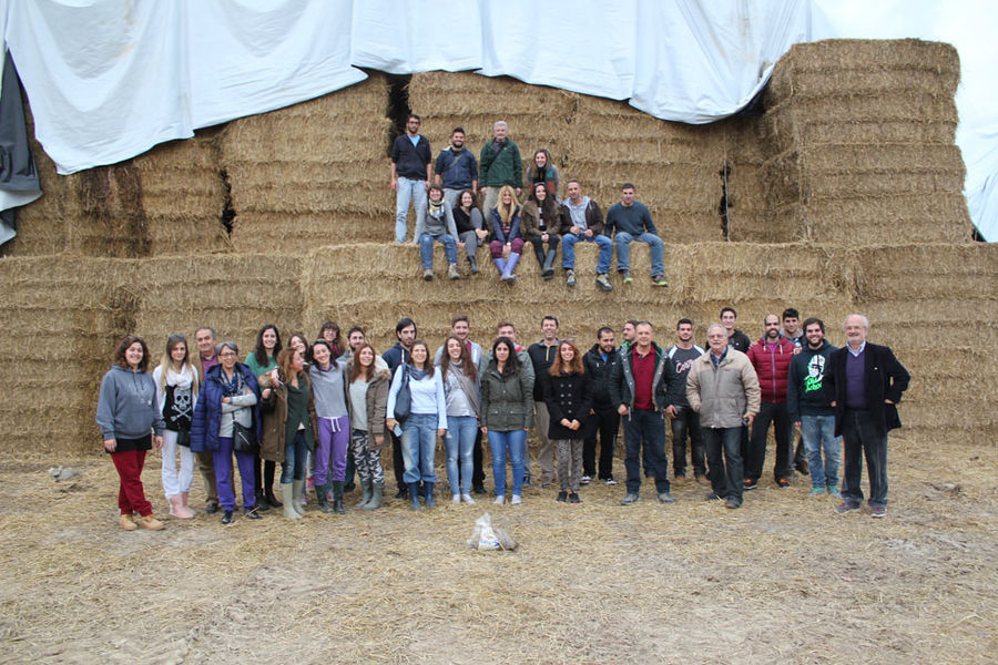 a group of tourists smiling to the camera and they have bales of hays in the background