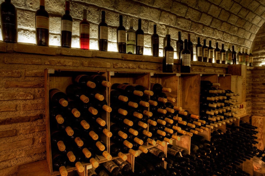 wine bottles on top of each other in the stone wall at 'Domaine Skouras' cellar