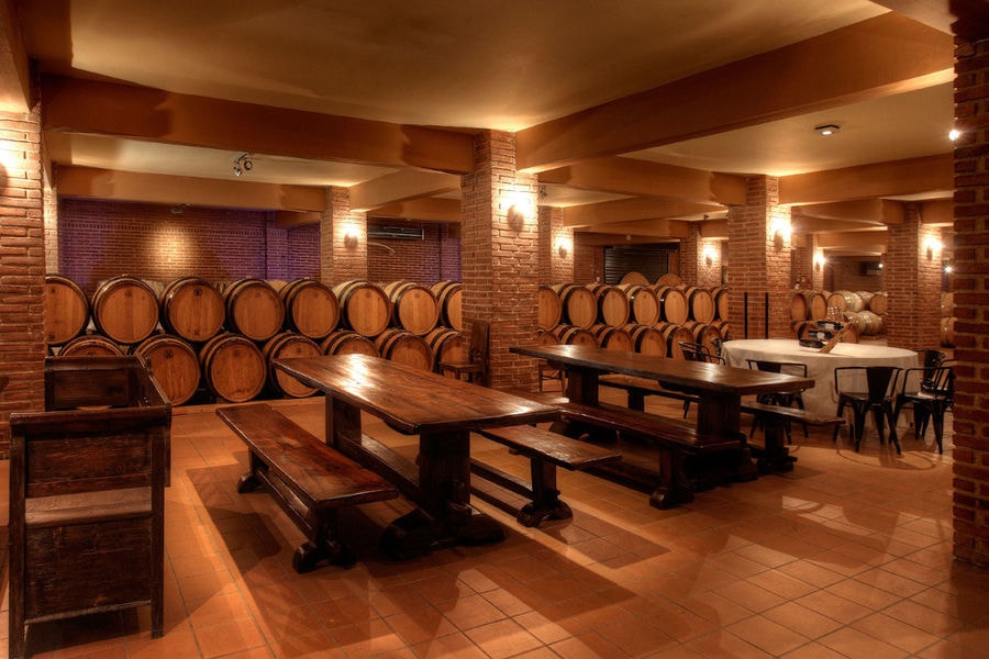 tables inside 'Domaine Skouras' cellar next to the wine wood barrels