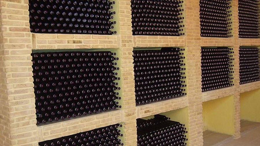 wine bottles on top of each other storaged in the stone wall in 'Domaine Anagennisi' cellar