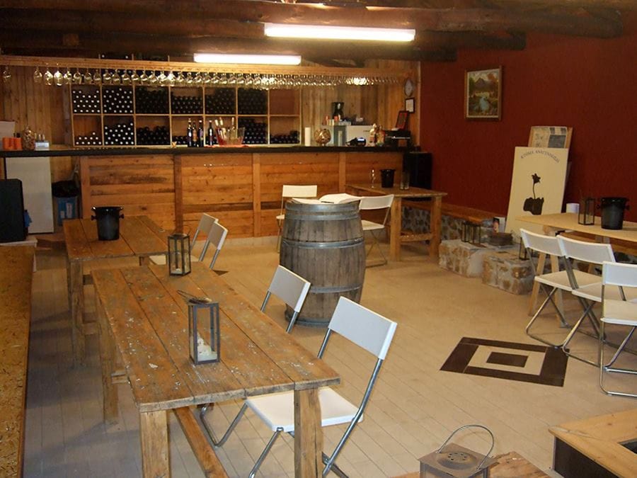 wood tables and chairs at 'Domaine Anagennisi' winery in the background of wine bar