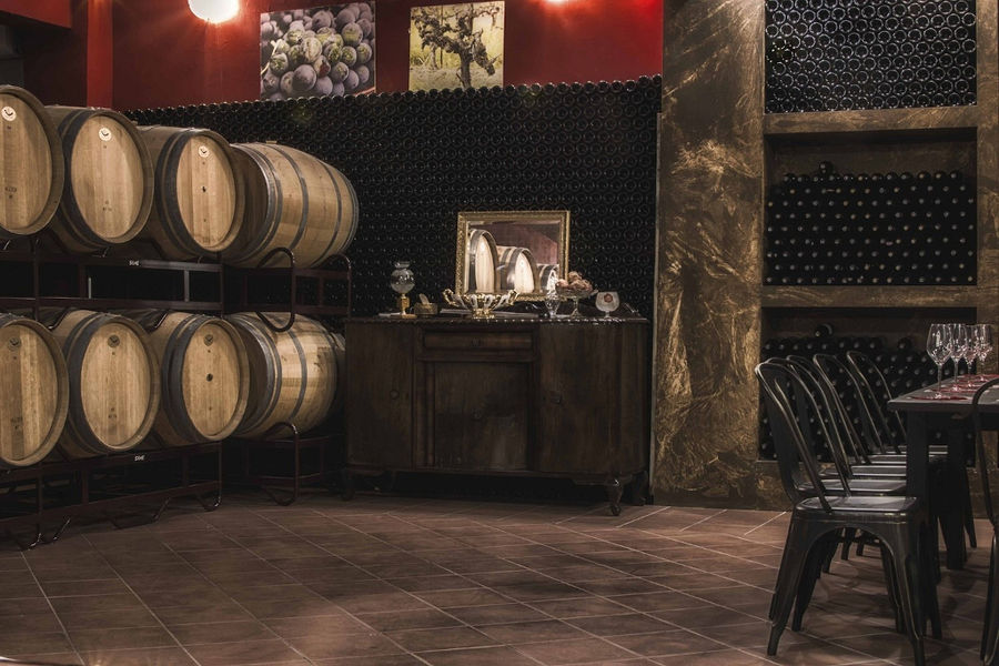 bottles in the storage locker and wine barrels and a wood cabinet at 'Domaine Bairaktaris' cellar