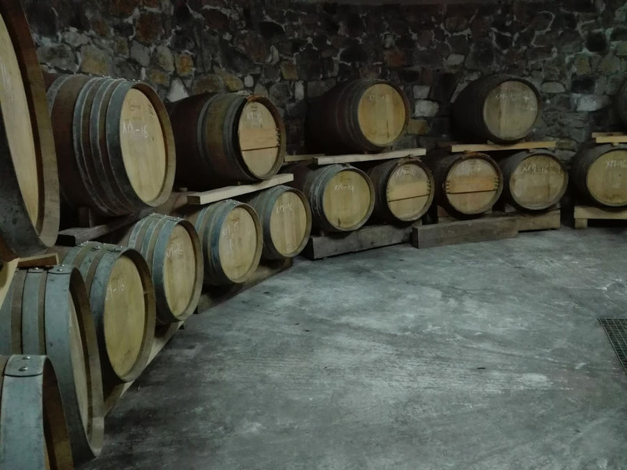 wine wood barrels on top of each other storaged in 'Domaine Karanika' stone cellar