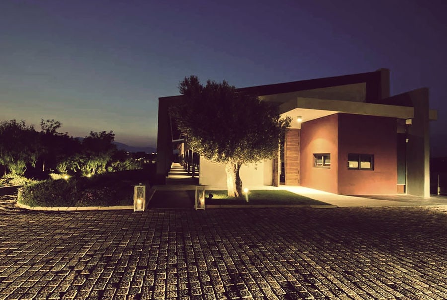 one side of the building with stone pavement and trees of Domaine Papagiannakos winery by night