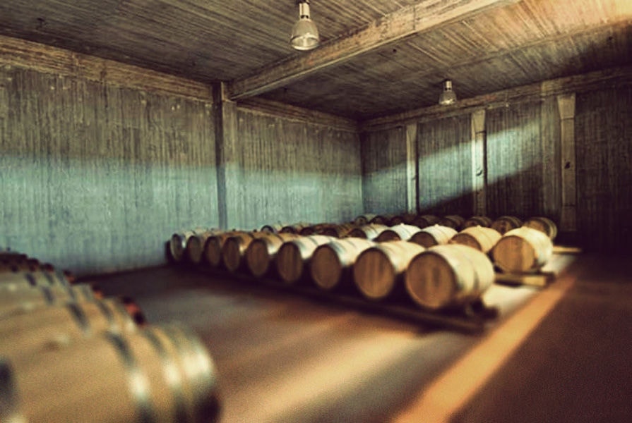 lying wine barrels in a row on the wood panels at Domaine Papagiannakos cellar