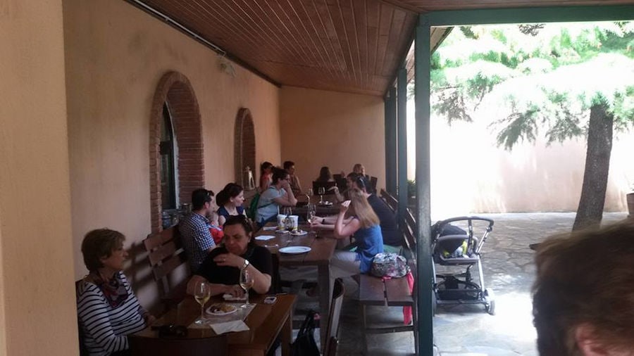 tourists sitting at the tables and tasting wines at 'Dougos Winery' outside