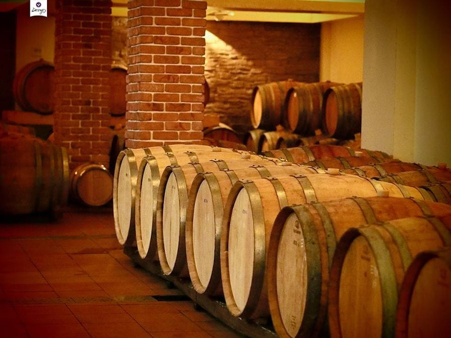 lying wooden barrels in a row at 'Dougos Winery' cellar with stone columns