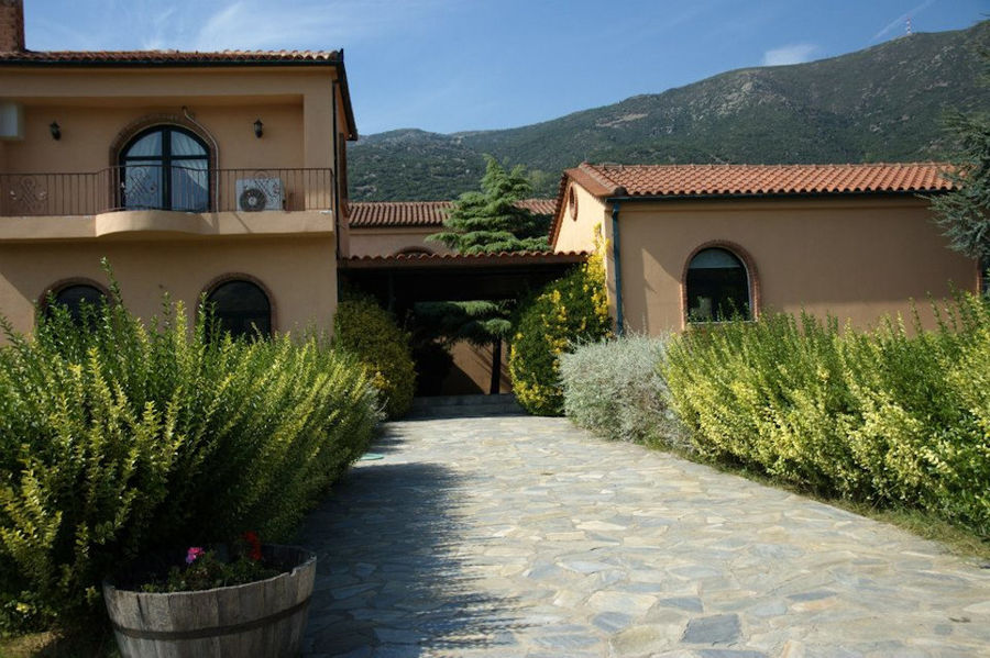 stone alley with bushes of plants on the both sides in front of 'Dougos Winery'
