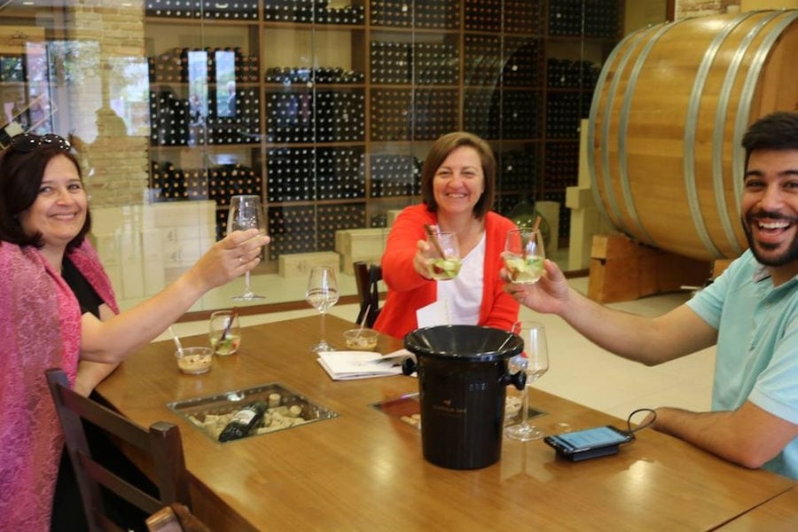 women and man smiling happily at the camera and tasting wine at Douloufakis Winery cellar