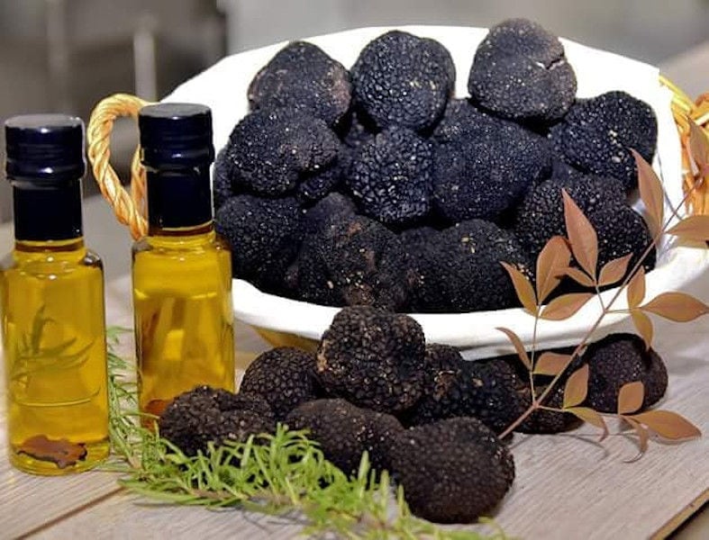 two bottles with oil and plate with fresh black truffles and a bush of rosemary from 'Dryas Greek Truffle'