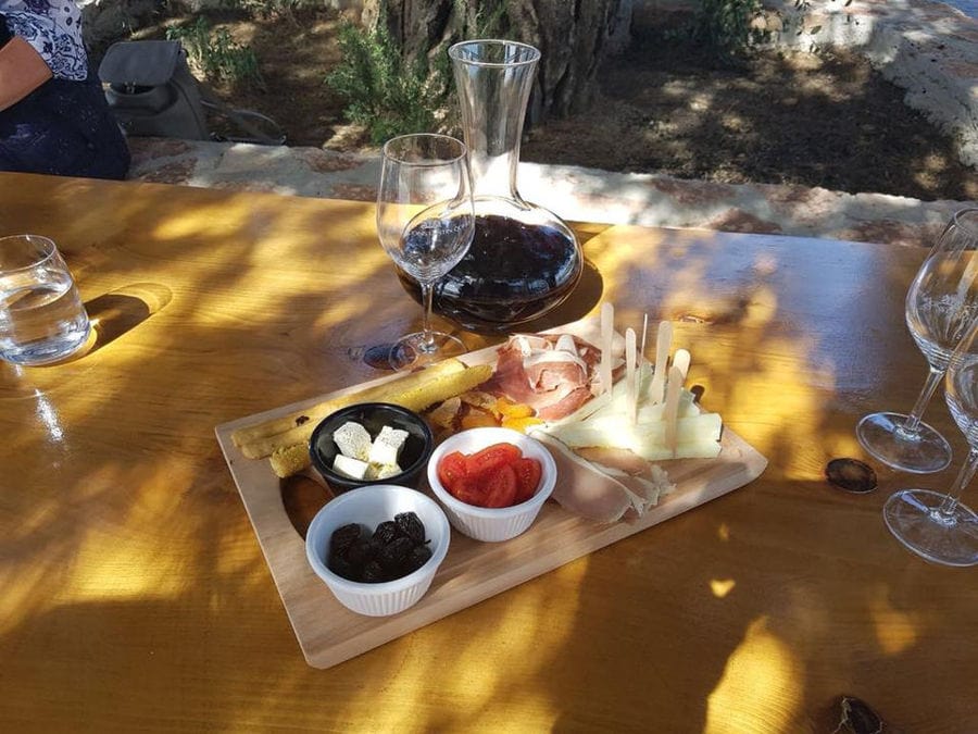 glasses and a bottle with wine and a plateau with spreads and cheeses on the table at Constantin Gofas Estate