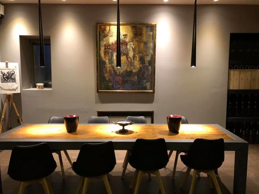 illuminated Constantin Gofas Estate room with wood tables and chairs and a painting on the wall