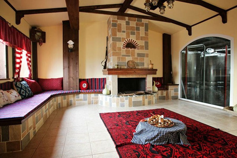 folklore living room with carpets and stone sofa and fireplace at 'Evritika Kellaria' winery