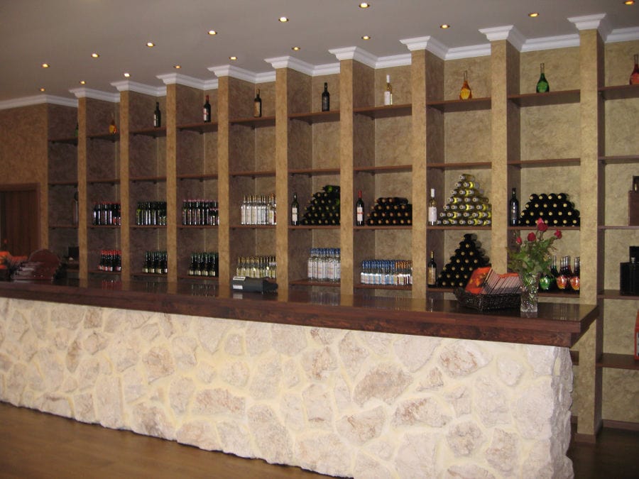 stone reception and bottles in the wall at 'Evritika Kellaria' wine bar