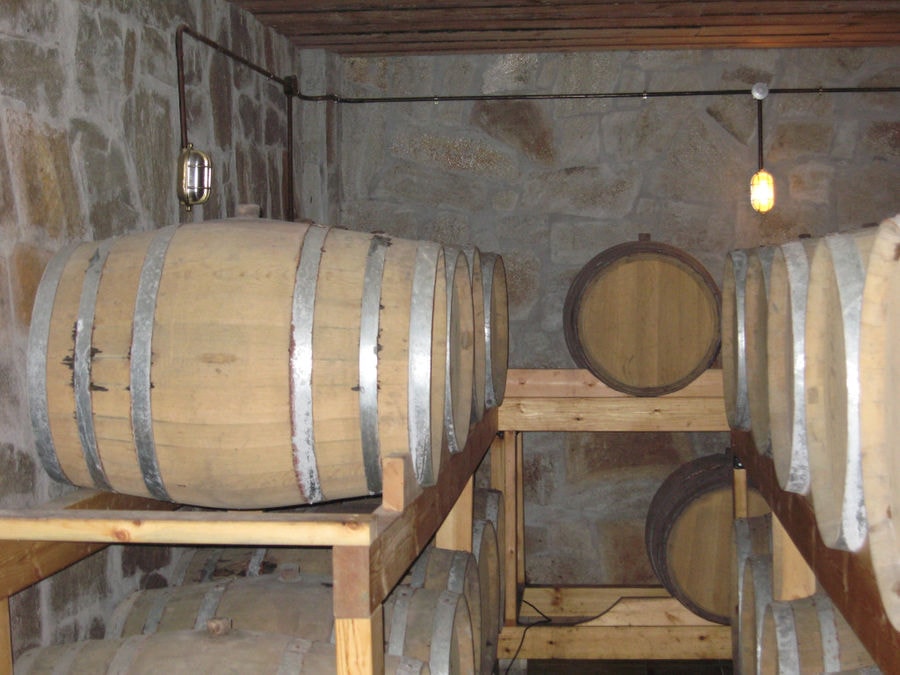 lying wine barrels in a row on the wood supports at 'Evritika Kellaria' stone cellar