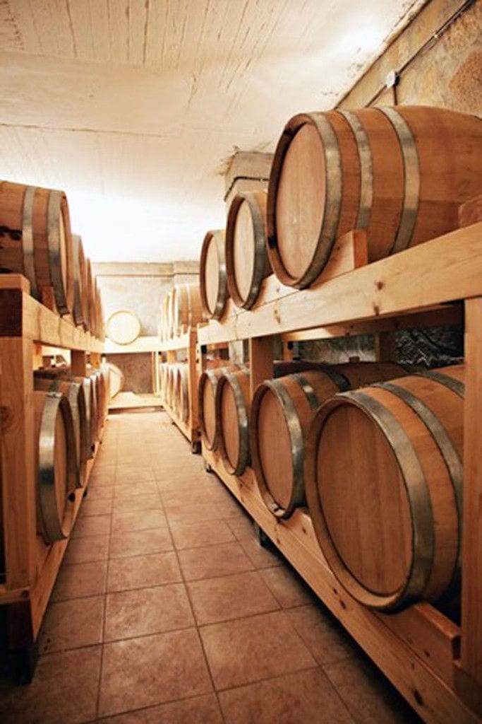 lying wine barrels in a row on the wood supports on top of each other at 'Evritika Kellaria' stone cellar