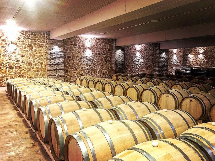 lying wine wooden barrels in a row at illuminated 'Filia Gi' stone cellar