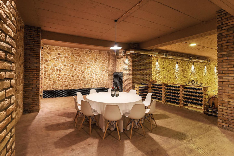 table with chairs and stacked bottles on top of each other by the wall of 'Filia Gi' stone cellar