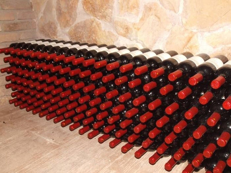 stacked bottles on top of each other on the wall of 'Filia Gi' stone cellar