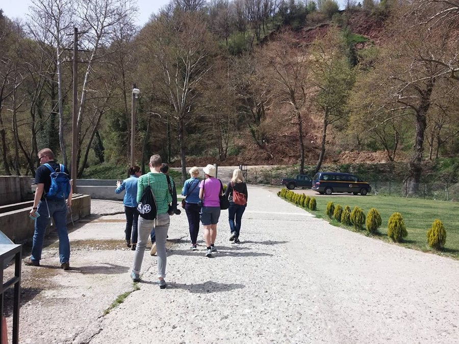a group of tourists walking on concrete path towards the mountains at 'Fresko'