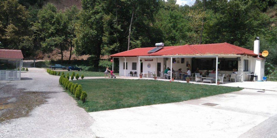 far view of tourists sitting on tables outside at Fresko's café and green lawn in the front