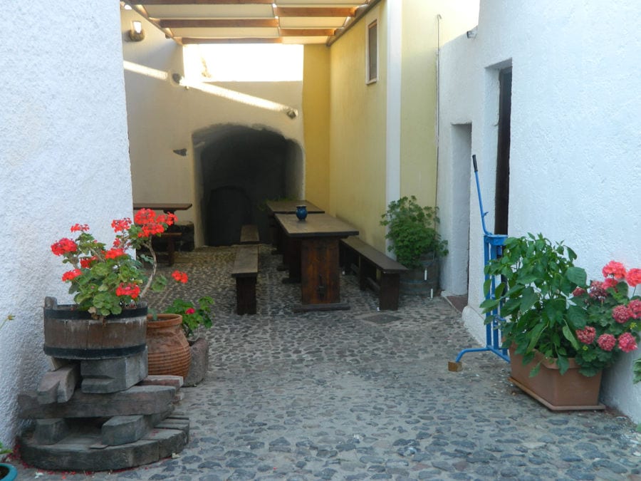 Gavalas Winery outside corridor with old press and table with branches and pots with flowers