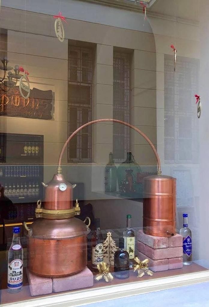 glasswindow with part of copper distillery and bottles at Karonis Distillery museum