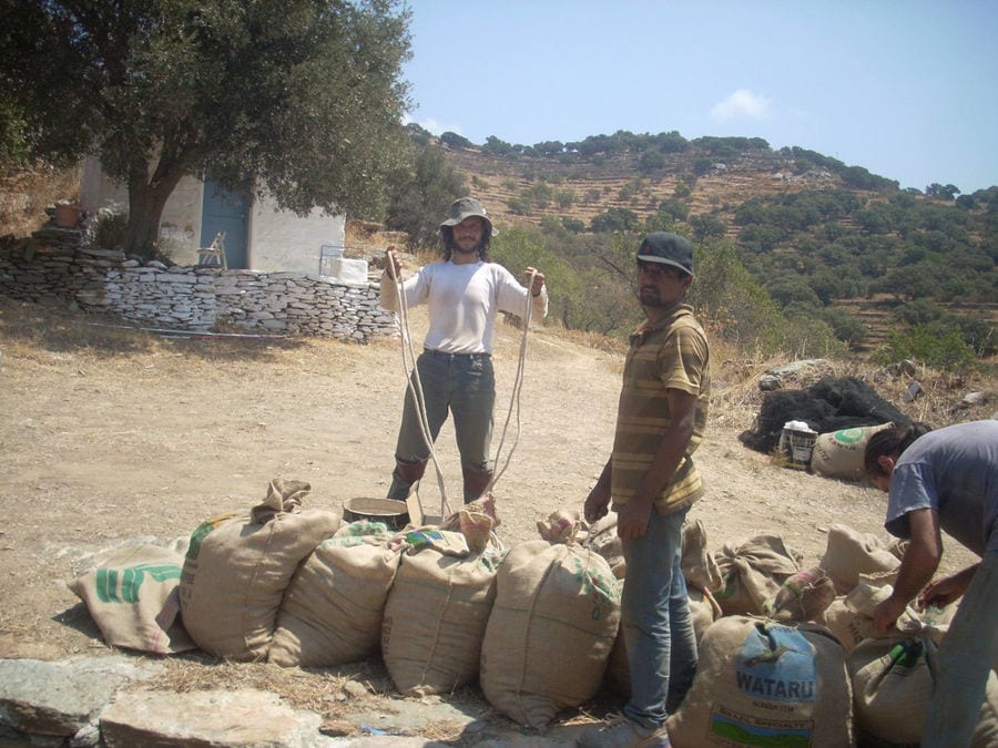 bags with almonds on the ground at 'Greek Almond' and two men watching at the camera