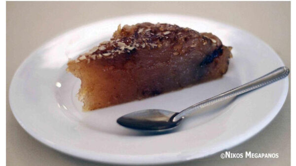 Close-up of plate with a piece of Greek ‘Halva Farsalon’ means pan-baked sweet covered with syrup and a sweet spoon