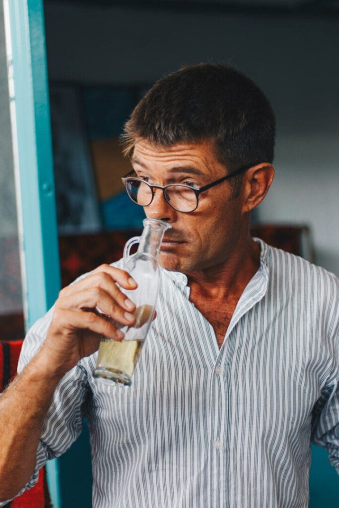 A man indulges in the sensory experience, delicately sniffing a bottle of white wine, his expression captivated by the anticipation of the wine's aromatic bouquet and its promise of refreshing delight.