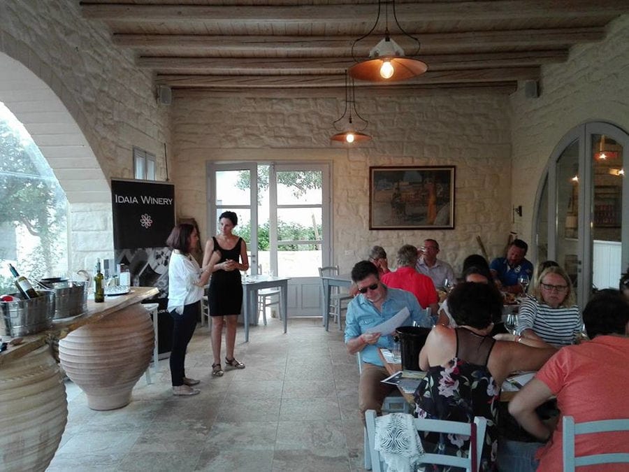 guide discussing with one woman and tourists sitting on the tables and enjoy a wine tasting at Idaia Winery
