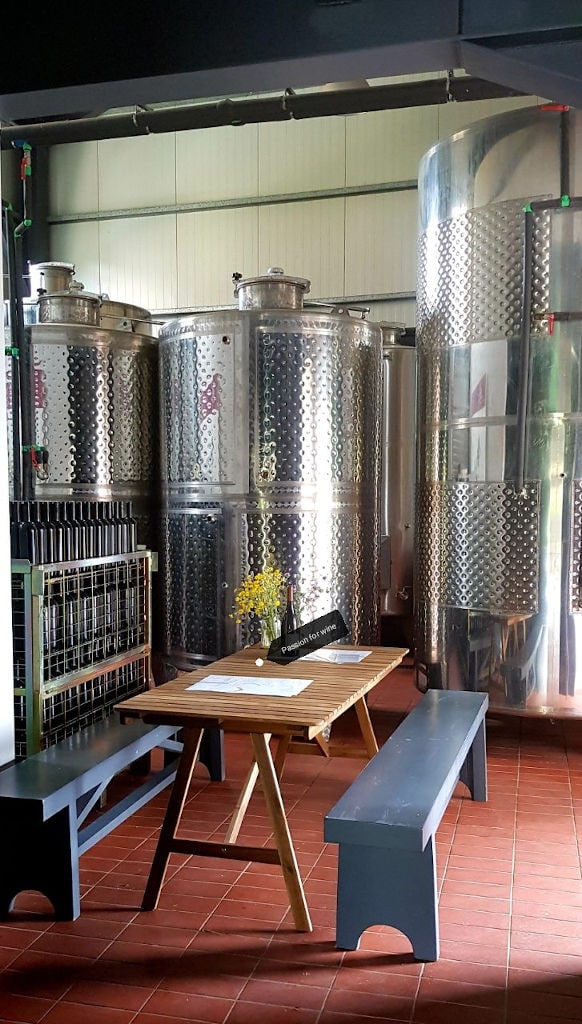 wood table with benches in front of the aluminum wine storage tanks at Idaia Winery facilities