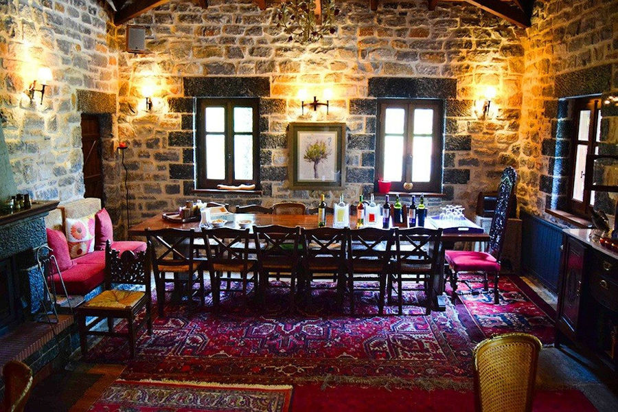 illuminated Kalogris Winery stone tasting room with folklore carpets and table with chair