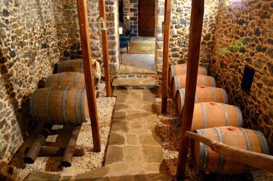 a corridor of Kalogris Winery stone cellar with wood barrels on the both sides