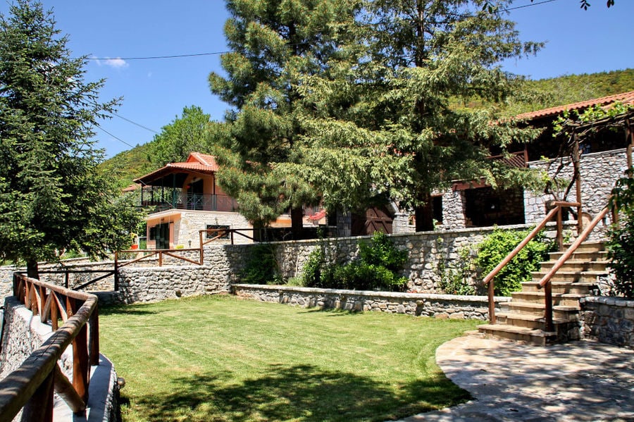 one side of Kalogris Winery stone building with pavement and green lawn and trees in the front