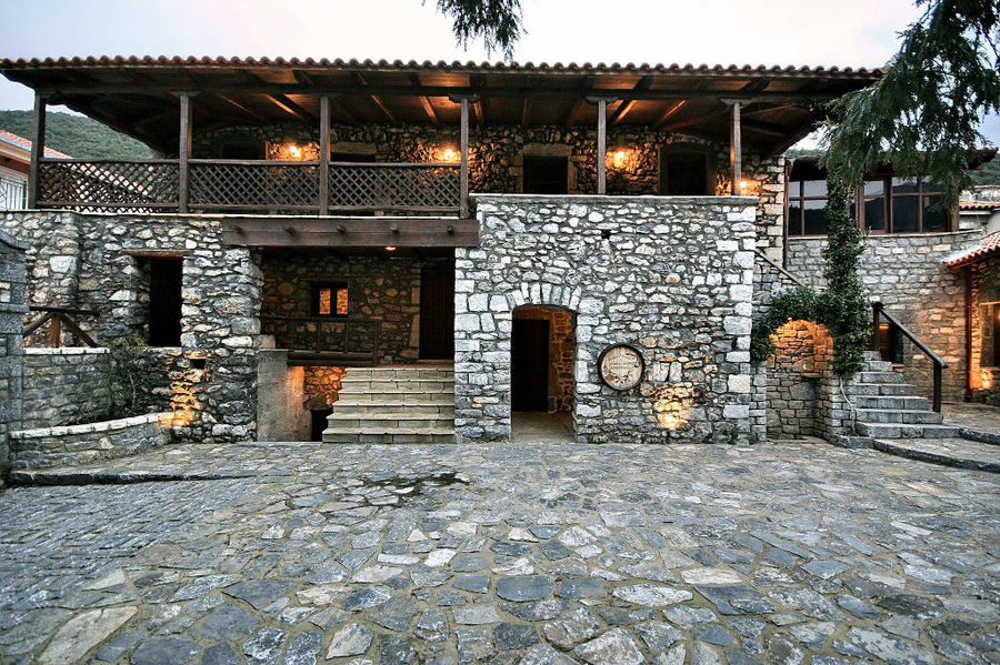 one side of illuminated Kalogris Winery stone building with pavement in the front