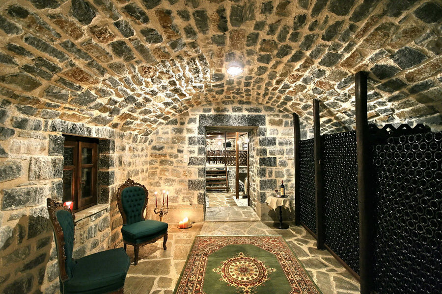 illuminated Kalogris Winery stone cellar with stacked bottles on top of each other on the one side