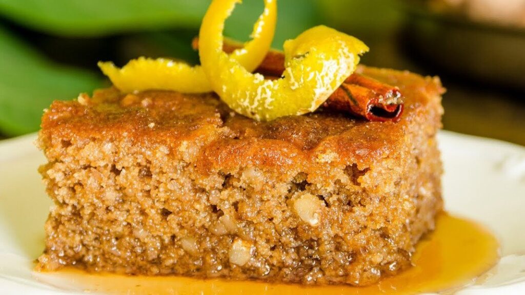 close-up of piece of Greek ‘Karydopita’ is a pan-baked sweet with nuts covered with syrup and lemon peel on top