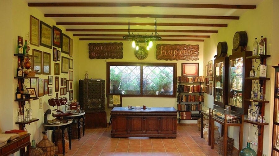 wooden desk in a room with antiquities and framed awards at Karonis Distillery museum