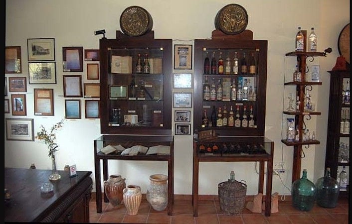 wooden lockers in a room with antiquities and framed awards at Karonis Distillery museum
