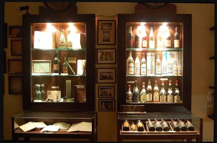 illuminated wooden lockers in a room with antiquities and framed photos at Karonis Distillery museum