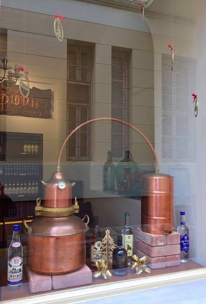 glasswindow with part of copper distillery and bottles at Karonis Distillery museum