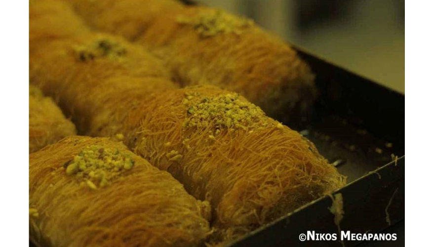 close-up of Greek ‘Kataifi’ sweet with thin leaves of pastry and dried nuts over which