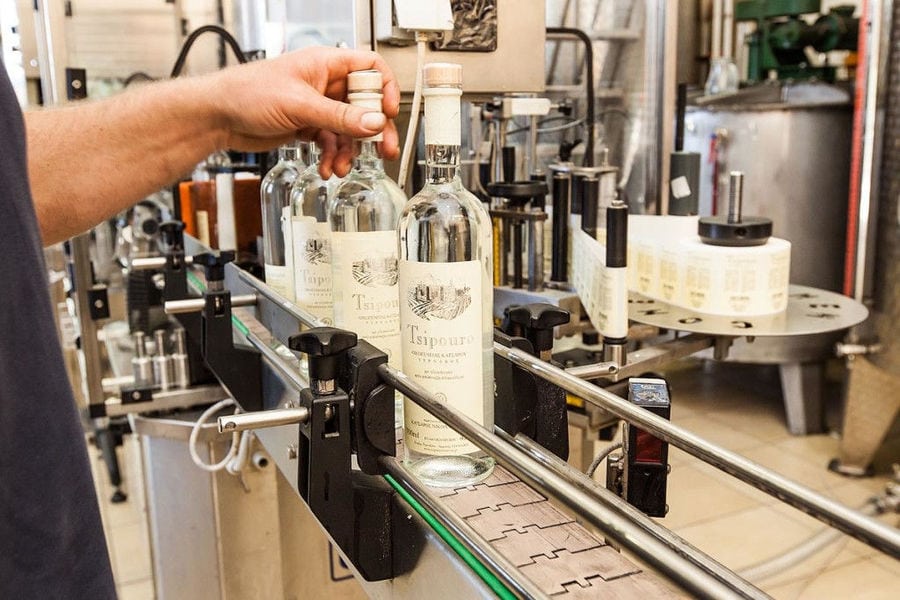 man capping off ouzo bottles in 'Katsaros Distillery'
