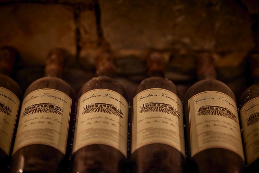 wine bottles on top of each other storaged in the stone wall in Kellari Papachristou cellar