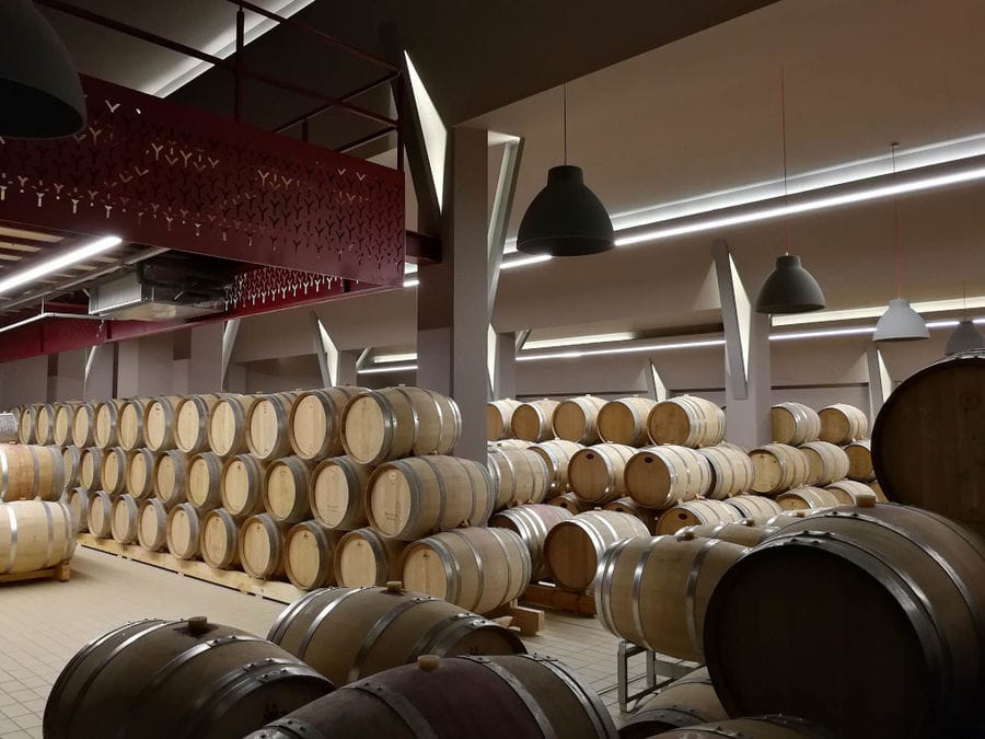 lying wine wood barrels on top of each other at illuminated Ktima Kir Yianni cellar
