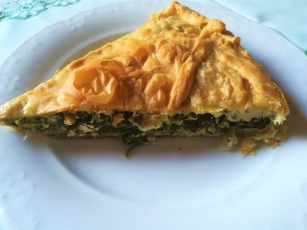 close-up of plate with a piece of ‘Kolopi’ means spinach pie